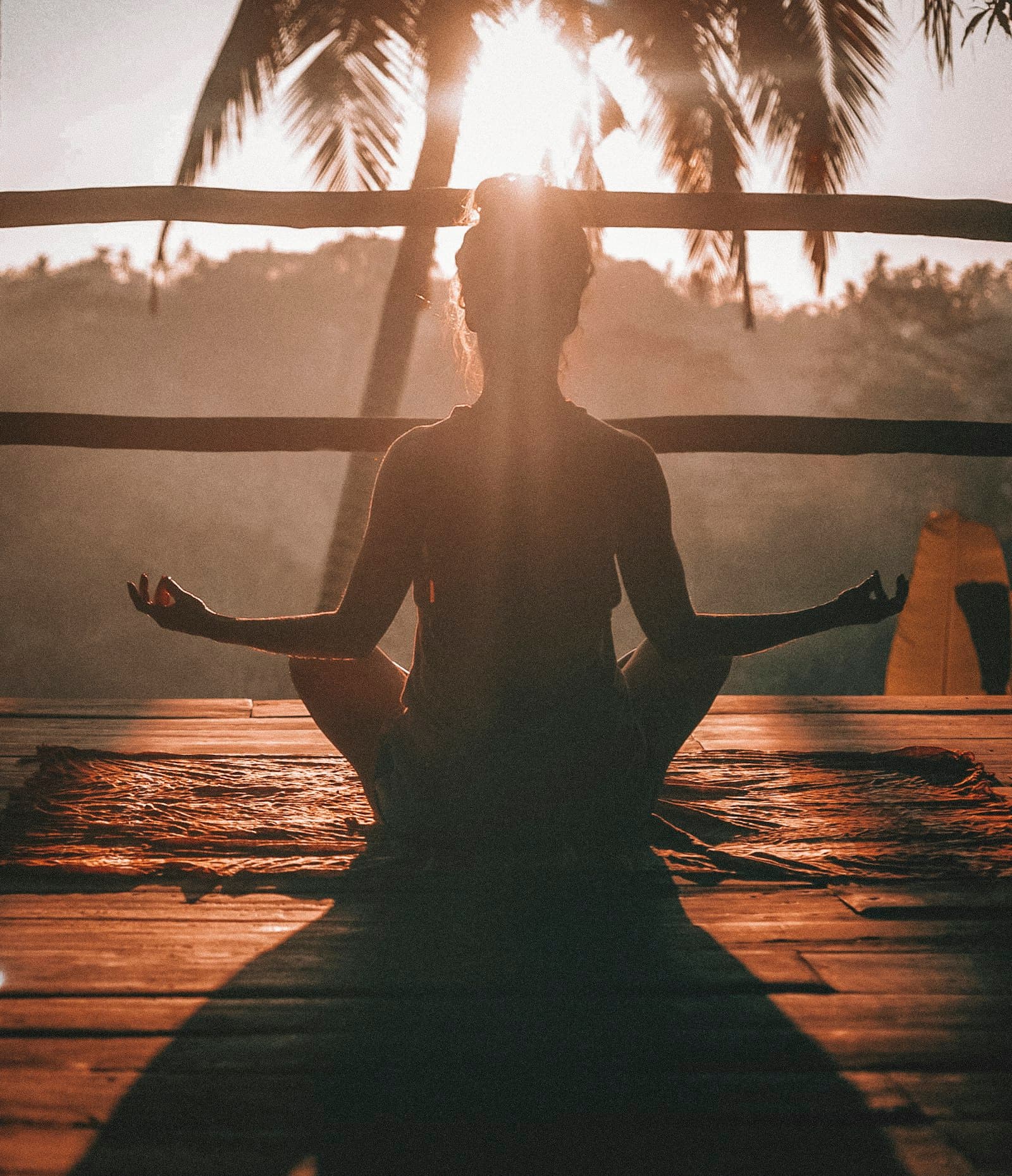 Mulher em postura de meditação sentada, mão sobre o peito, luz natural suave